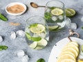 Summer citrus lemonade with ice in two bulging glasses, sugar in little white plate, slices of citrus on a ceramic white board on Royalty Free Stock Photo