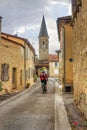 Summer city landscape - back view of a cyclist who rides down a medieval street, in the historical province Gascony