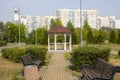 Summer city park, paved path and wooden gazebo against the backdrop of residential buildings