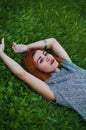 Summer close up portrait of pretty smiling young woman, laying on the grass, enjoy her vacation, natural make up red Royalty Free Stock Photo