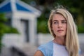 Summer Closeup portrait of beautiful blond girl with long hair and beautiful eyes poses against a white fence . She Royalty Free Stock Photo