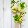 Summer cocktail, water detox with lemon, ice and mint in mason jar on a white wooden background. Top view. Royalty Free Stock Photo