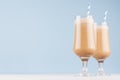 Summer coffee cocktails with cream, striped straws for breakfast in transparent glass in soft pastel blue interior on white wood. Royalty Free Stock Photo