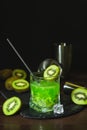 Summer cold drink and beverages. Alcohol coctail with kiwi and ice in whiskey glass on black table Royalty Free Stock Photo