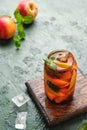 Summer cold drink, iced tea with nectarine or peach, ice and mint in a glass beaker on a green concrete background. Soft drinks, Royalty Free Stock Photo