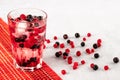 Summer cold drink with water, ice and multicolor berries. A glass of red and black currants on a gray background. Fruitarianism, Royalty Free Stock Photo