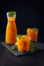 Summer cold drinks: homemade peach sangria with ice , and mint in glass on wooden black background