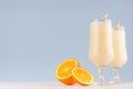 Summer cold fresh milk cocktail of orange with juicy pieces fruit, straw on white wood board and soft pastel blue wall, copy space Royalty Free Stock Photo