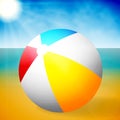 Summer colored rubber inflatable beach ball on abstract beach background. Royalty Free Stock Photo