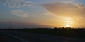 summer colorful golden sunset over meadows stretching along empty highway and power lines. Royalty Free Stock Photo