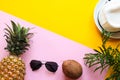 Summer composition. Coconut, pineapple, palm tree leaves, sunglasses, and hat on a pink-yellow background with copy spase. Royalty Free Stock Photo