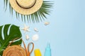 Summer composition flat lay. Round trendy rattan bag straw hat tropical palm leaves coconut sunscreen seashells on blue background Royalty Free Stock Photo