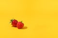 Summer composition fruits, berries. Two of freshly ripened strawberries on a yellow background