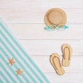 Summer composition, towel, beach slippers, hat, sunglasses on white wood, summer background Royalty Free Stock Photo