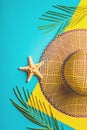 Summer composition. Tropical palm leaves, straw beach hat, starfish on pastel blue and yellow background. Concept summer