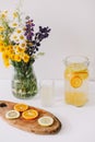 Summer concept. Bouquet of wild natural flowers. Homemade lemonade with orange and lemon. Healthy  fresh cool beverage Royalty Free Stock Photo