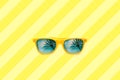 Summer concept image: yellow sunglasses with palm tree reflections isolated in large yellow striped background. Royalty Free Stock Photo