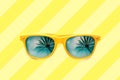 Summer concept image: yellow sunglasses with palm tree reflections isolated in pastel yellow striped background Royalty Free Stock Photo