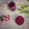 Summer concept of making cherry jam in glass jar close up on gray fabric background