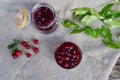 Summer concept of making cherry jam in glass jar close up on gray fabric background