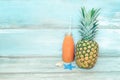 Summer concept stillife - ripe pineapple and a bottle of multivitamin juice in front of a blue rustic wooden background Royalty Free Stock Photo