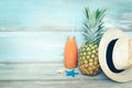 Summer concept stillife - ripe pineapple, straw hat and a bottle of multivitamin juice in front of a blue rustic wooden background Royalty Free Stock Photo