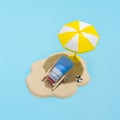 Summer concept. Sunscreen cream on sand and sun umbrella on blue background. Skin care concept in summer