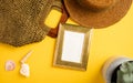 Summer concept.Top view golden picture frame mockup with straw hat ,seashell and bag on vivid yellow background Royalty Free Stock Photo