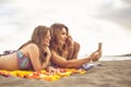 Summer concept tourists with three friends girls lay down on the beach for a sunbath together taking selfie picture with smart