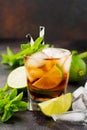 Summer cooling alcoholic beverage from cola, whiskey, lime and liqueur in glass on dark concrete old background.