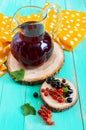 Summer cooling drink - compote of berries black, red currant in a jug on a bright background.