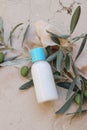 Summer cosmetic still life scene. Oil, shampoo or cream bottle mockup with blue cap. Olive tree branches, fruit on beige Royalty Free Stock Photo