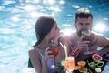 Summer couple with cocktail and fruit swimming at sea. Cocktail at man and girl on Maldives. Pool party relax in spa