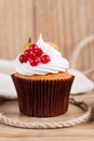 Summer cupcake with whipped cream and fruits on wooden background