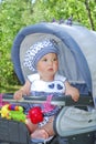 In summer, cute little girl sitting in a pram and smiling. Royalty Free Stock Photo