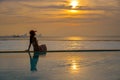 Summer day, asian young woman happy in big hat relaxing on the swimming pool, travel near the sea and beach in the sunset. Royalty Free Stock Photo