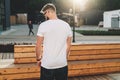 Back view. Young bearded hipster man dressed in white t-shirt and sunglasses is stands on city street. Mock up. Royalty Free Stock Photo