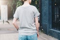 Back view. Young millennial woman dressed in gray t-shirt is stands on city street. Mock up. Royalty Free Stock Photo