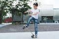 Summer day. The boy is a teenager dressed in a white T-shirt and jeans, skating, doing tricks. Royalty Free Stock Photo