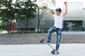 Summer day. The boy is a teenager dressed in a white T-shirt and jeans, skating, doing tricks. Royalty Free Stock Photo