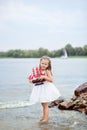 Summer day. Happy childhood carefree game on the open sand. The concept of rest. Little cute girl and scarlet sails. Girl sitting Royalty Free Stock Photo