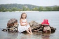 Summer day. Happy childhood carefree game on the open sand. The concept of rest. Little cute girl and scarlet sails. Girl sitting Royalty Free Stock Photo