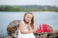 Summer day. Happy childhood carefree game on the open sand. The concept of rest. Little cute girl and scarlet sails. Girl sitting Royalty Free Stock Photo