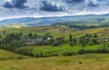 Summer day landscape with road, cloudy sky and small houses. Ukraine, Carpathian. Royalty Free Stock Photo