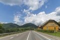 Summer day landscape with road, cloudy sky and small houses. Ukraine, Carpathian. Royalty Free Stock Photo