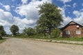 Summer day landscape with road, cloudy sky and small houses. Ukraine, Carpathian. Royalty Free Stock Photo