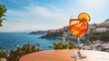 Summer day on the shores of the Mediterranean Sea, where a refreshing glass of Aperol Spritz cocktail awaits on a table in a