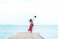 Summer Day. Smiling women relax and wearing red dress fashion standing on the wooden bridge over the sea, blue sky background. Royalty Free Stock Photo