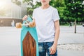 Young millennial boy dressed in white t-shirt is stands outdoor. Mock up. Space for logo, text, image.