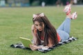 Girl resting on grass. Summer day. Young smiling woman in sunglasses lying on green lawn. Girl listens to music on Royalty Free Stock Photo